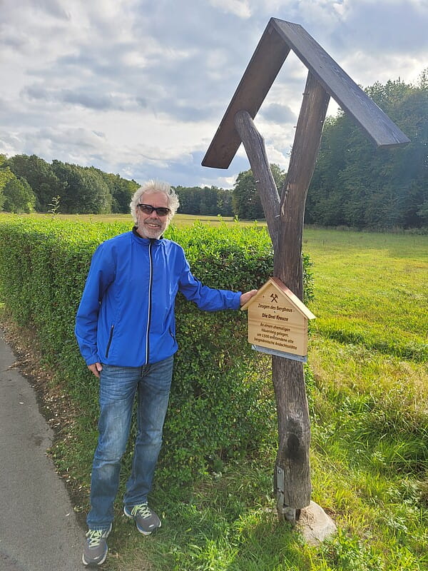 Neuer Look an neuem Standort: Alexander Henker, einer von vier 2022 neu berufenen Ortswegewarte, präsentiert stolz das frisch angebrachte Holzhäuschen zu den Drei Kreuzen